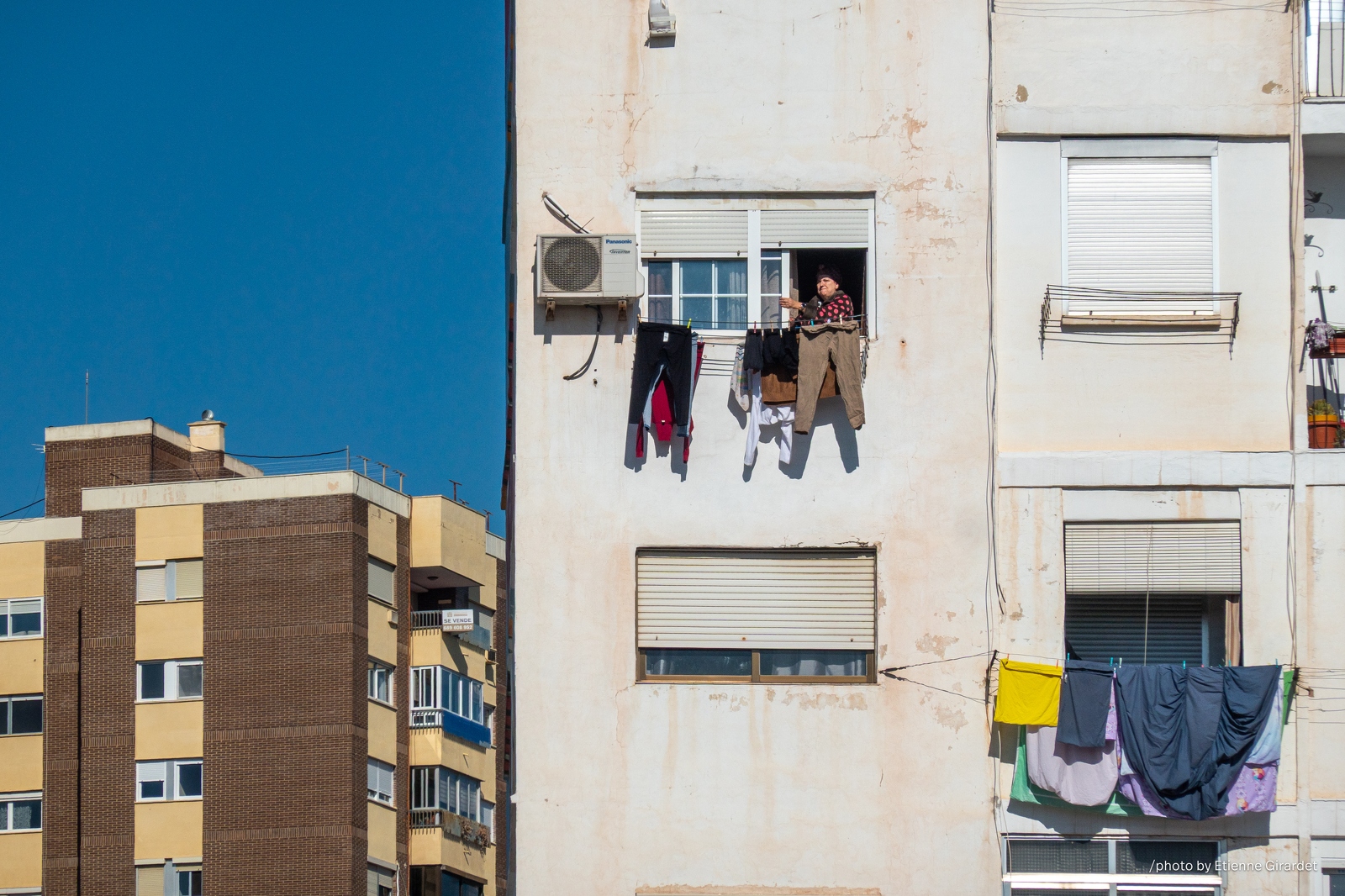202302_01_RXX02517-woman-drying-clothes-on-balcony-apartment-building-by-E-Girardet.jpg