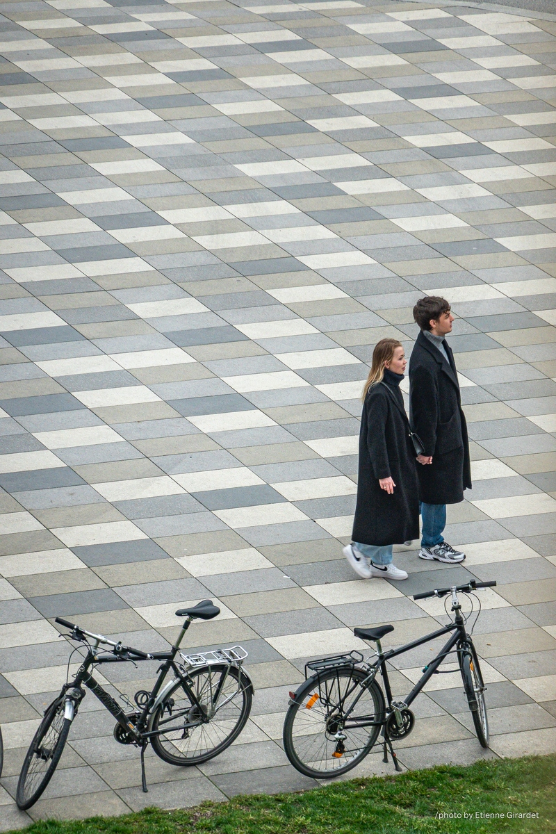 202304_16_RXX03047-couple-walks-on-patterned-pavement-with-bikes-by-E-Girardet.jpg