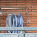 202312_16_ZZ63885-light-blue-and-gray-clothes-on-rack-against-brick-wall-by-E-Girardet.jpg