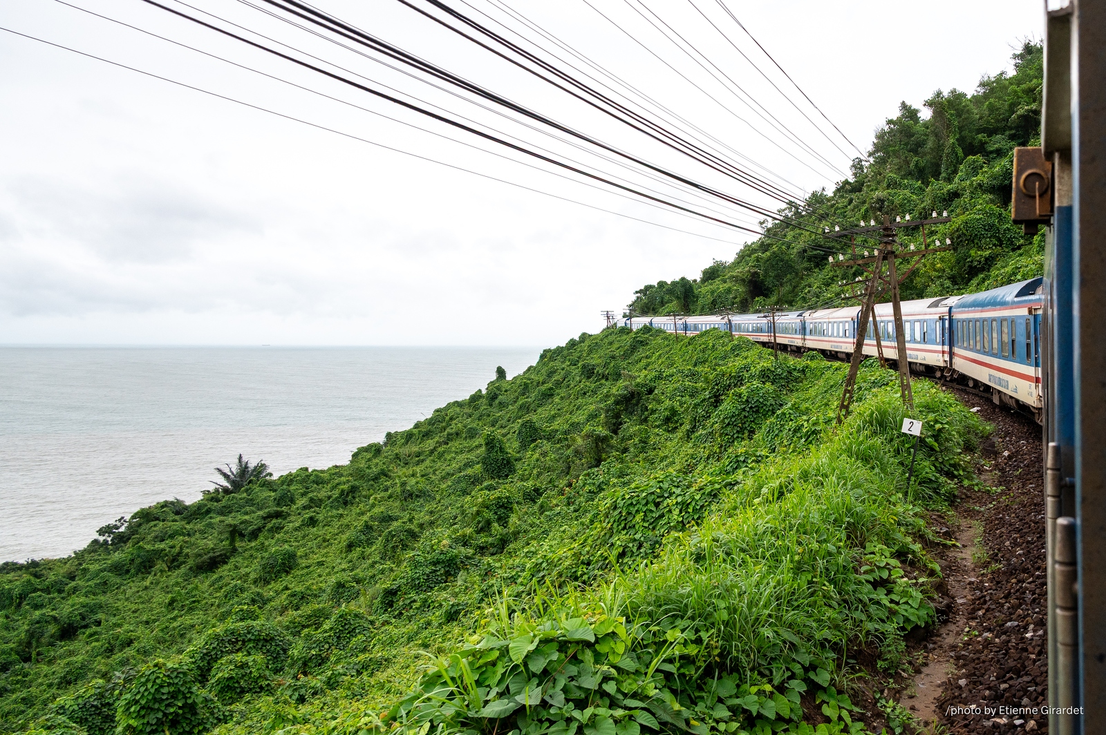 202312_28_ZZ64682-train-tracks-winding-through-lush-hillside-by-ocean-by-E-Girardet.jpg